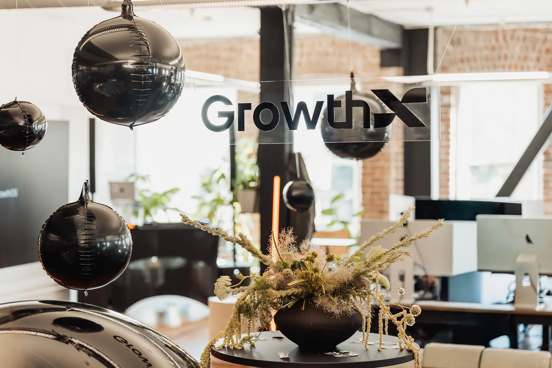 GrowthX logo framed by hanging black balloons and flowers at GrowthX Launch Party