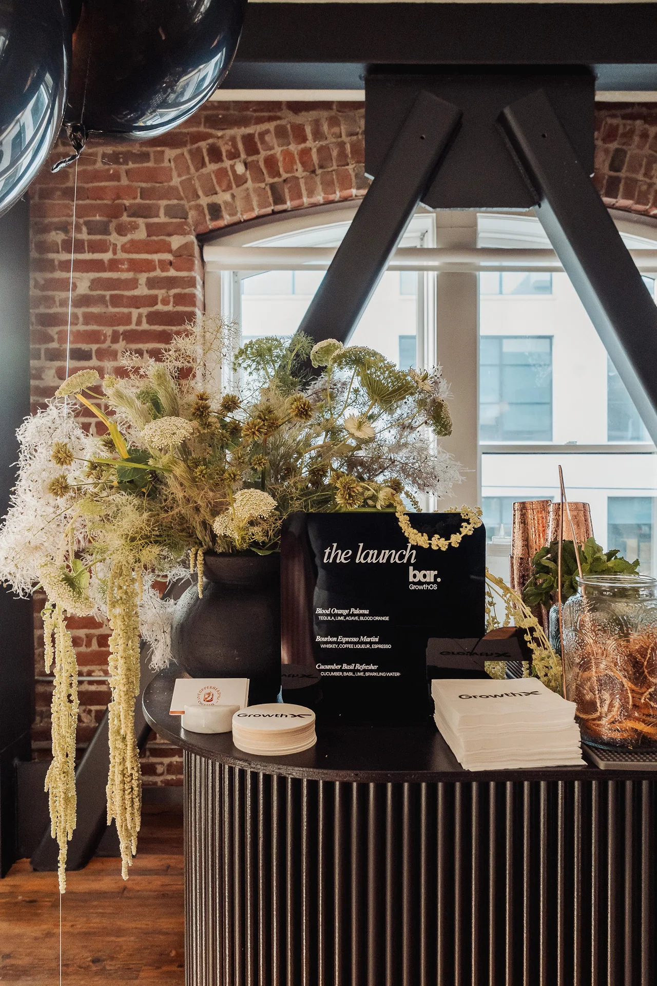 Floral arrangement and event signage on a ribbed pedestal at GrowthX Launch Party