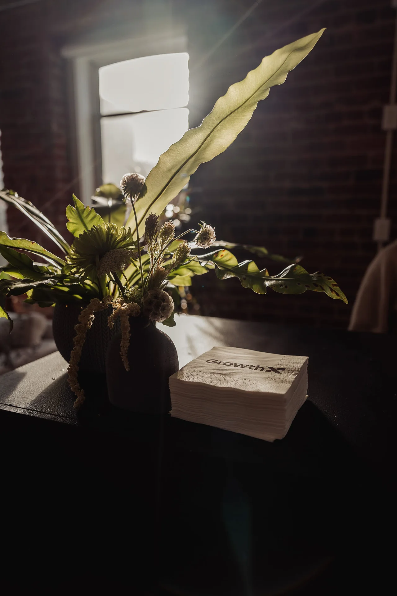 Sculptural greenery and pale flowers in a dark vase at GrowthX Launch Party
