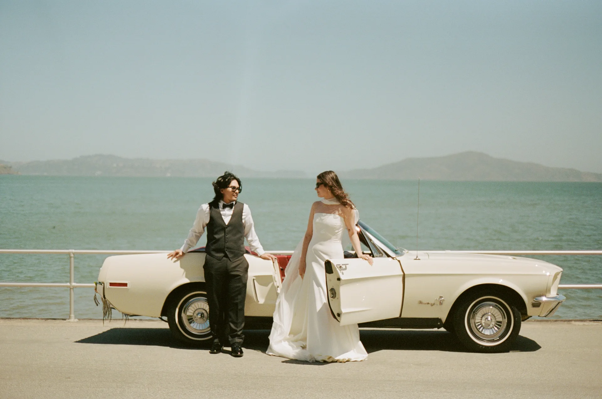 Couple beside a white Mustang along the waterfront at A&M Wedding