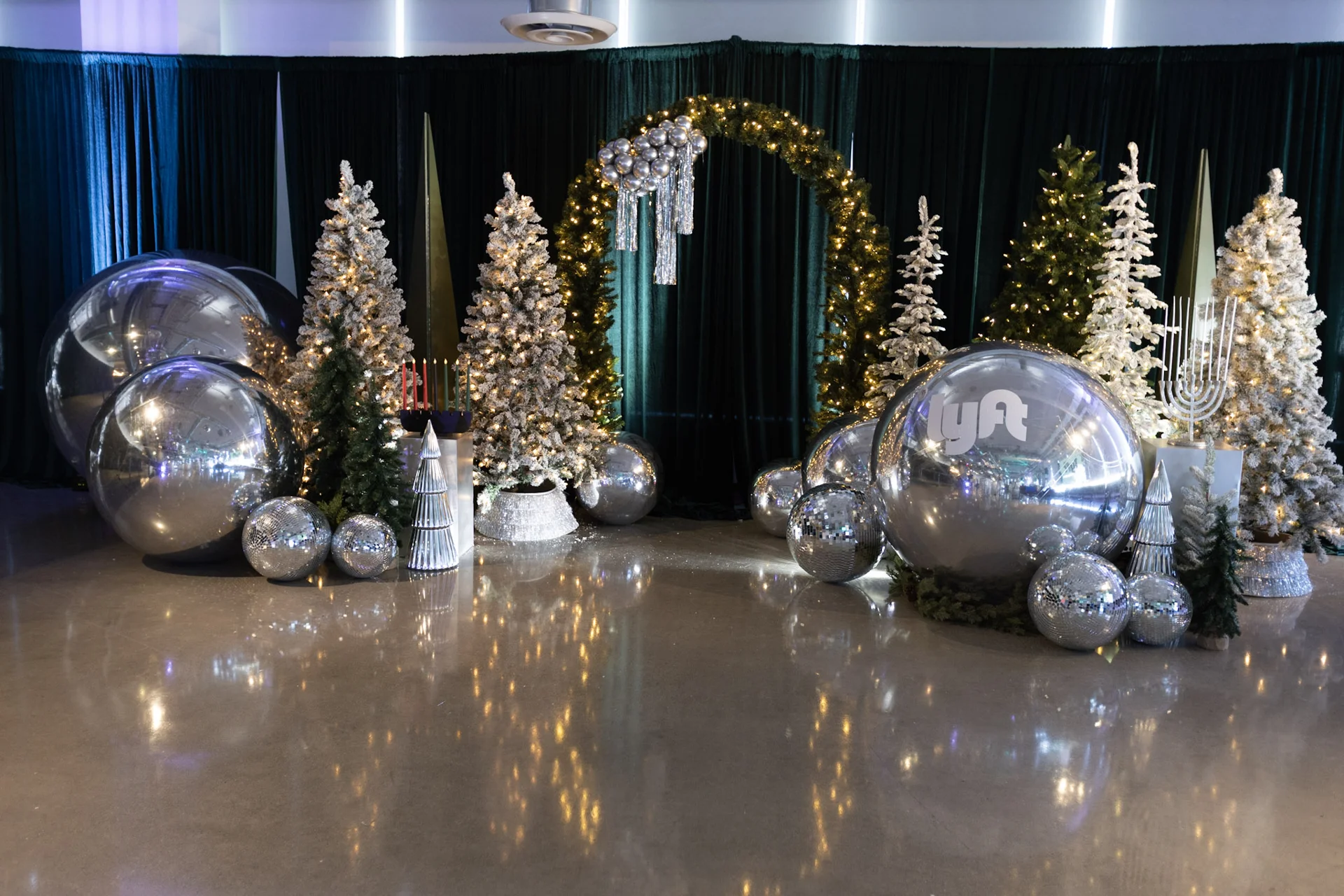 Lyft Holiday Party backdrop with illuminated trees, a garland arch and branded silver balloons