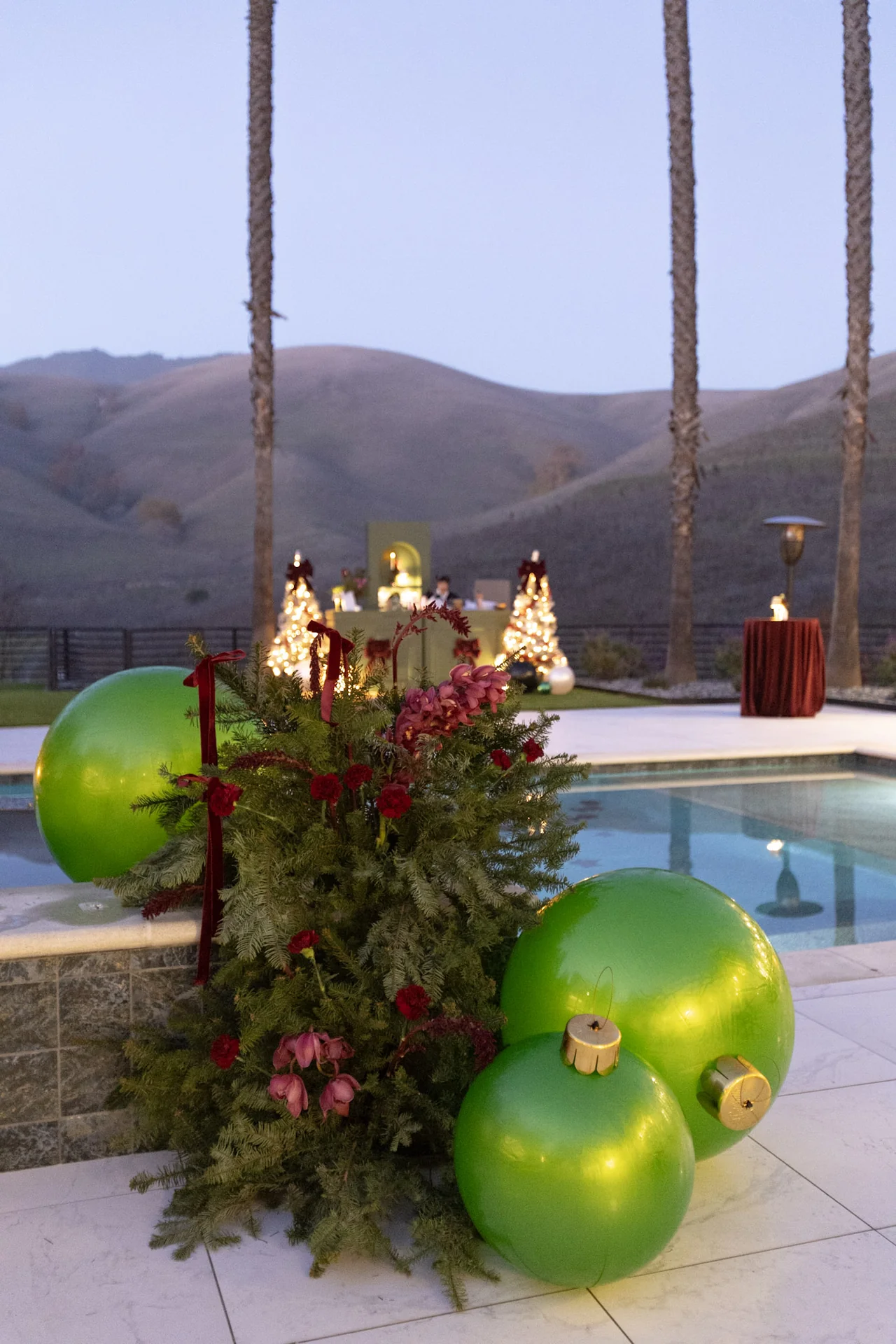 Red holiday florals beside the pool at M&E Company Holiday Party