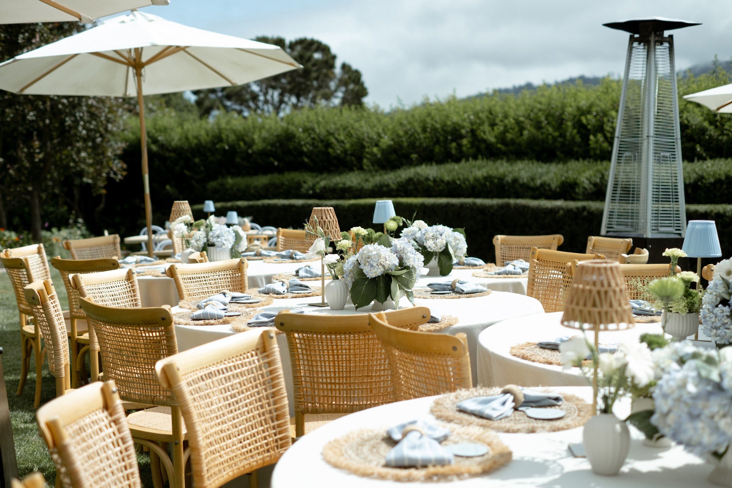 Garden celebration with woven chairs and blue and white floral tables