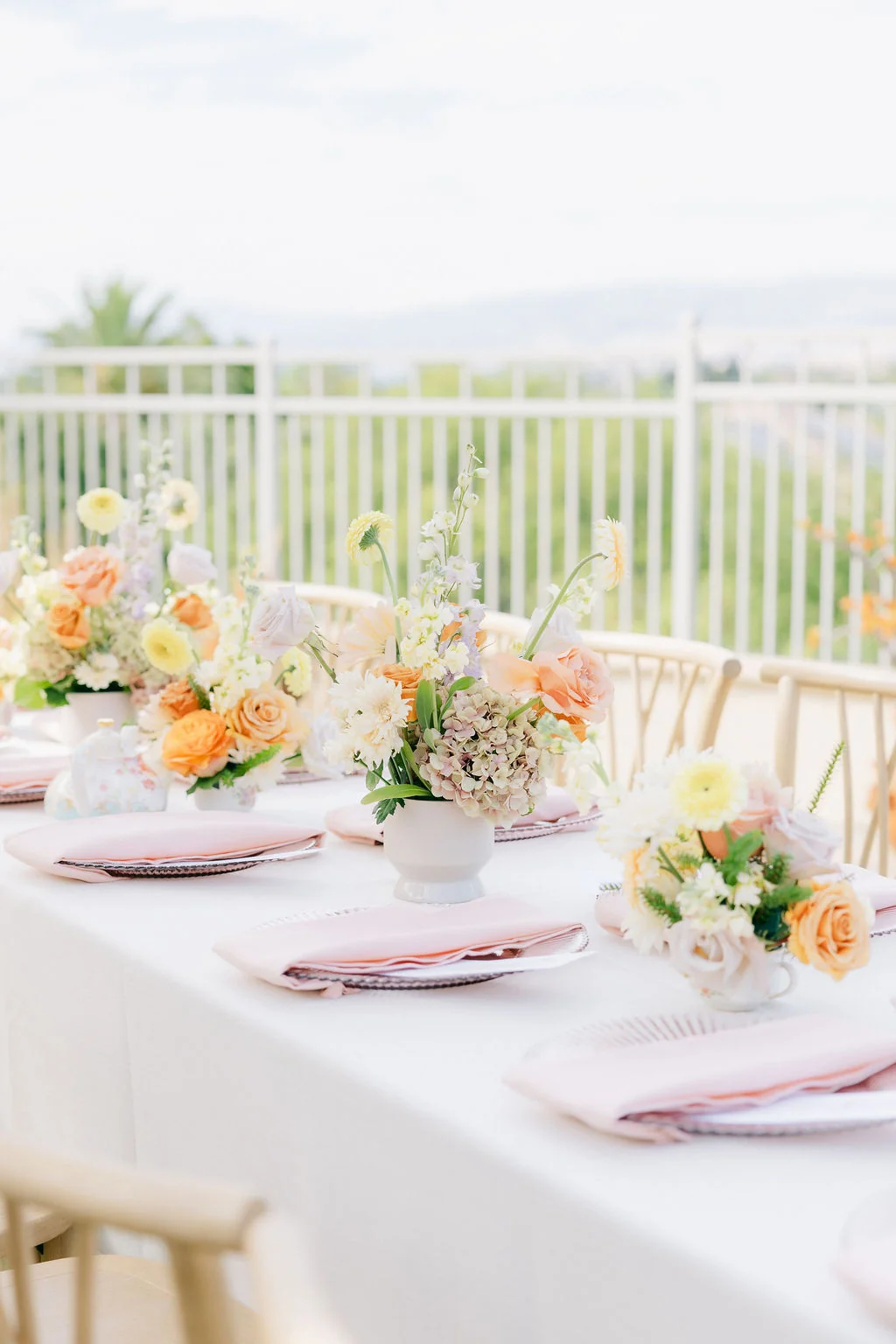 Pastel flowers and pink place settings on a white dining table at Tea Party Bridal Shower