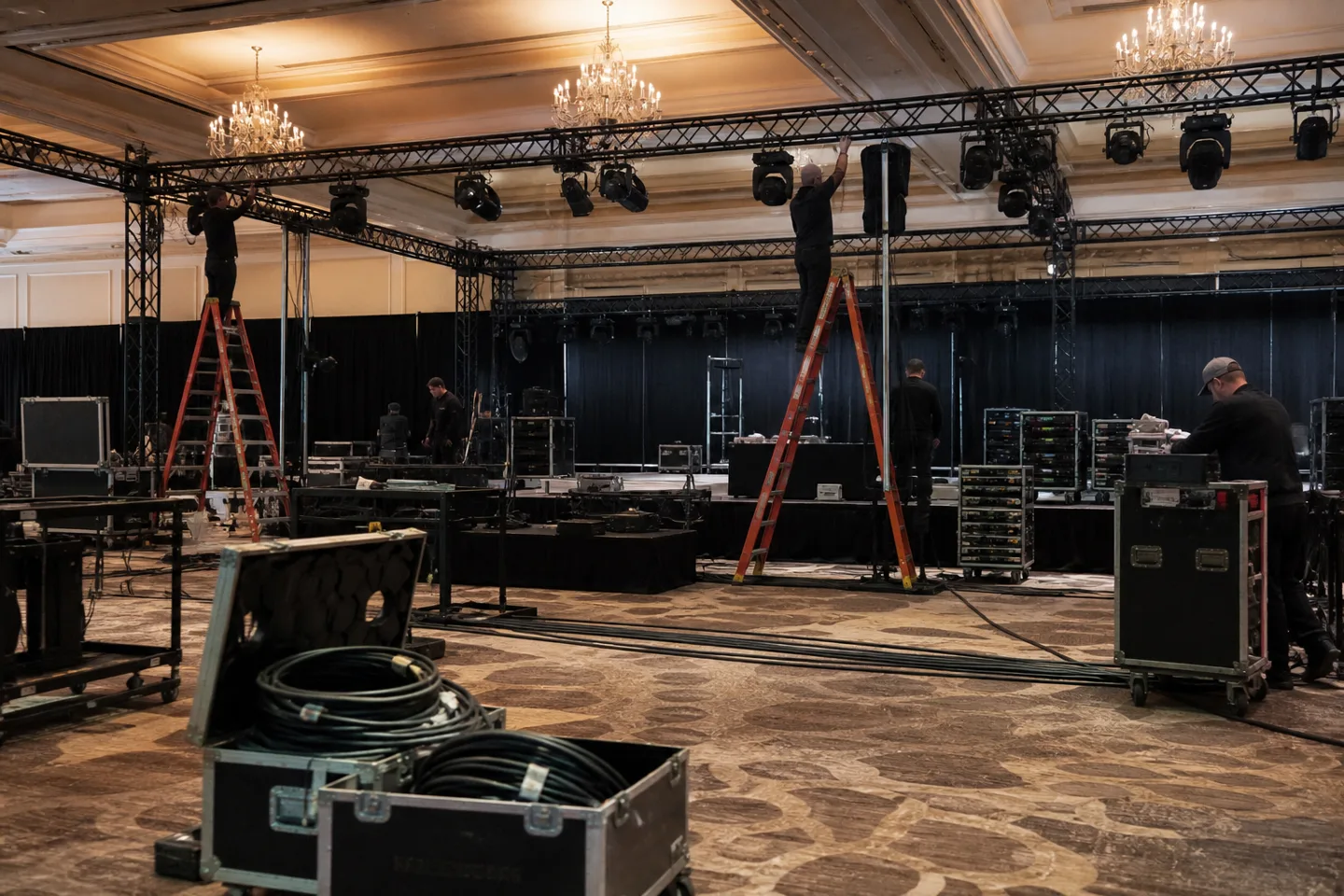 Technical crew installing lighting and staging in a ballroom